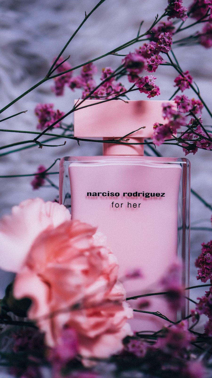 Pink perfume bottle framed by delicate blossoms
