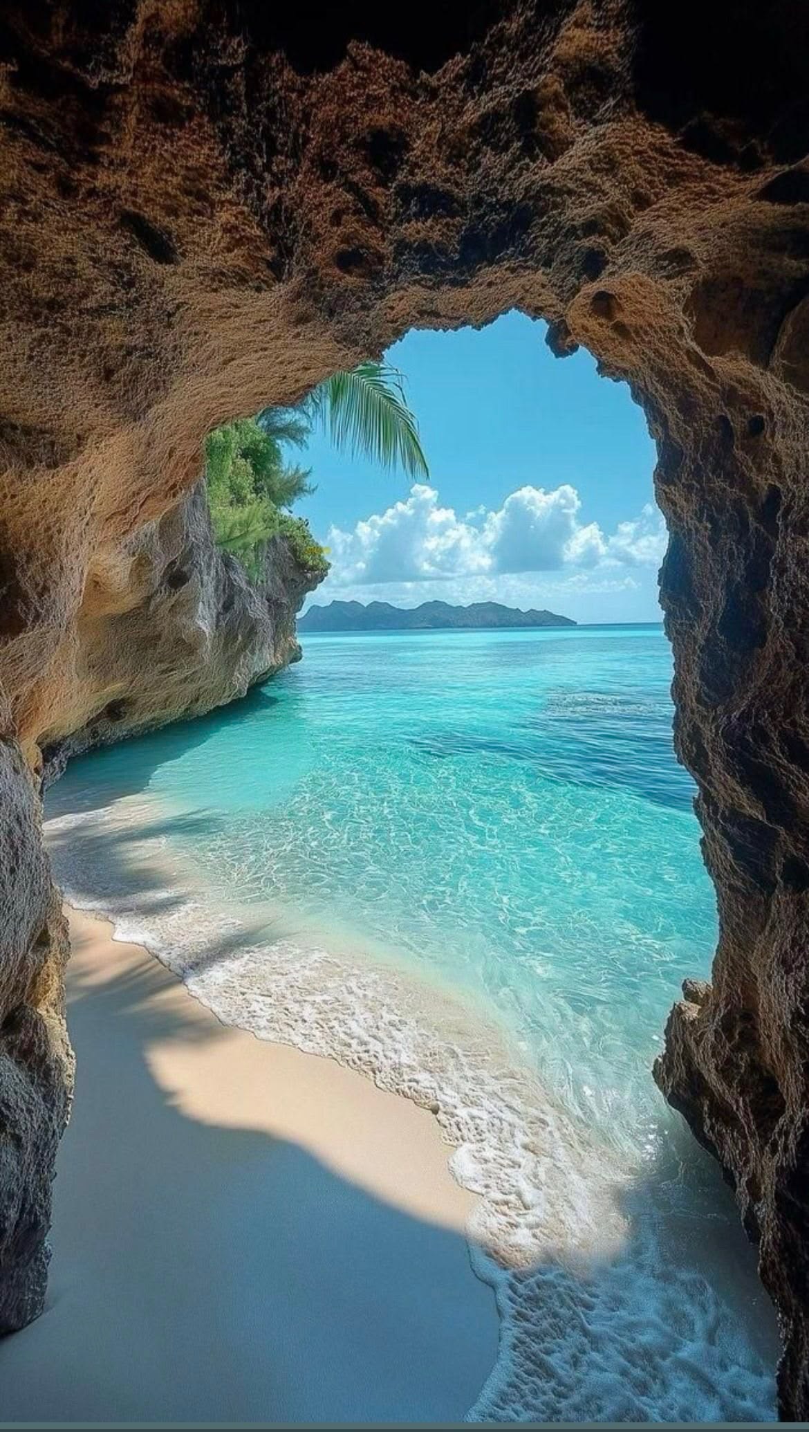 Turquoise sea and sandy beach viewed through a coastal cave